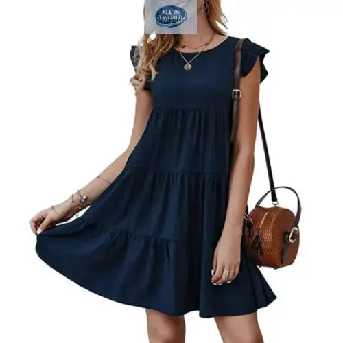 Short navy blue flowy tiered dress with ruffled cap sleeves - Elegant loose-fit summer mini dress for women with a round neckline - Styled with a brown leather bag - ALL IN 1 WORLD