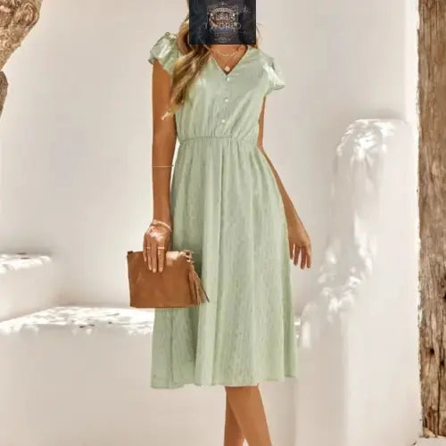 Full front view of a sophisticated sage green Swiss dot midi dress featuring a V-neckline and ruffled cap sleeves - Elegant flowy summer dress with an elasticated waist for a flattering fit - ALL IN 1 WORLD