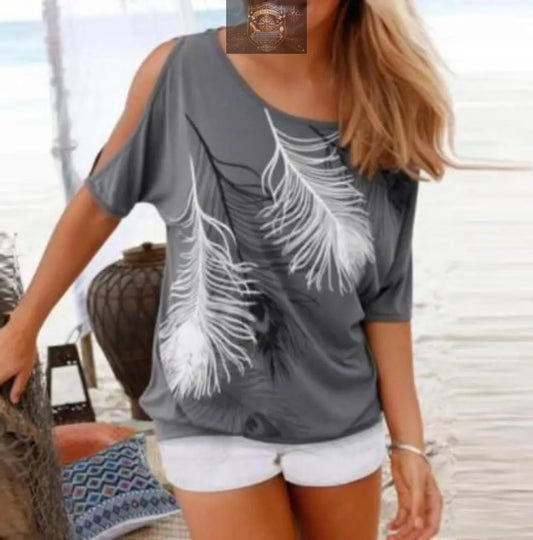 Lifestyle shot of a woman in a grey feather print t-shirt paired with white denim shorts - Showing the cold-shoulder cut-out detail and relaxed beachy fit - Perfect summer vacation outfit - ALL IN 1 WORLD