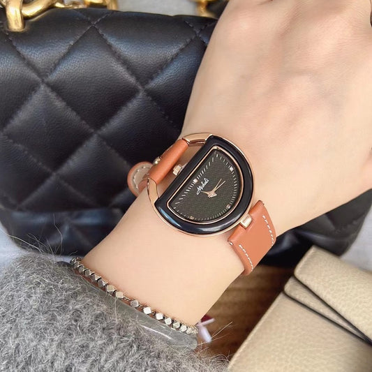 Half-moon dial watch with brown strap worn on the wrist