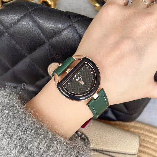 Half-moon dial watch with green strap worn on the wrist