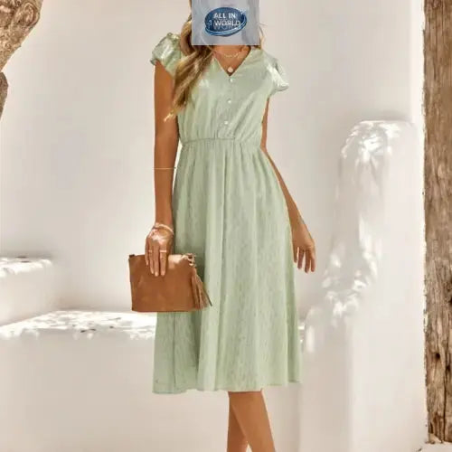 Full front view of a sophisticated sage green Swiss dot midi dress featuring a V-neckline and ruffled cap sleeves - Elegant flowy summer dress with an elasticated waist for a flattering fit - ALL IN 1 WORLD