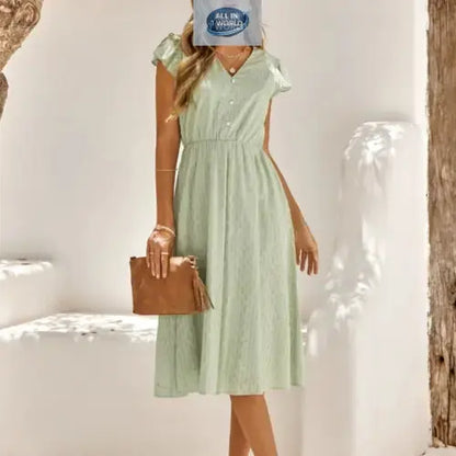 Full front view of a sophisticated sage green Swiss dot midi dress featuring a V-neckline and ruffled cap sleeves - Elegant flowy summer dress with an elasticated waist for a flattering fit - ALL IN 1 WORLD