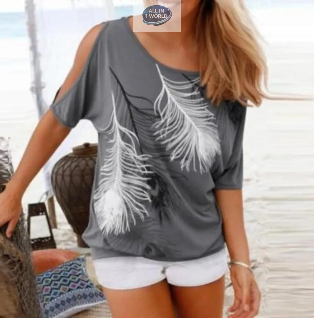 Lifestyle shot of a woman in a grey feather print t-shirt paired with white denim shorts - Showing the cold-shoulder cut-out detail and relaxed beachy fit - Perfect summer vacation outfit - ALL IN 1 WORLD
